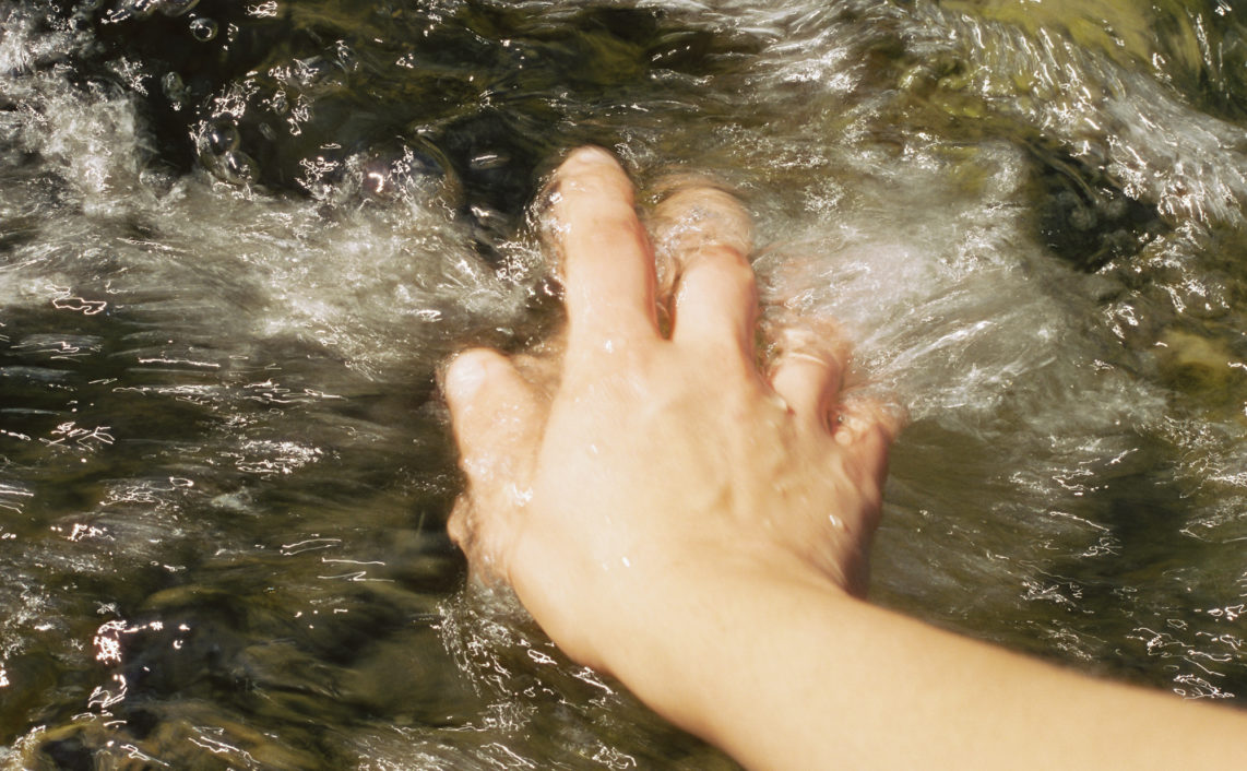 river current washes over hand